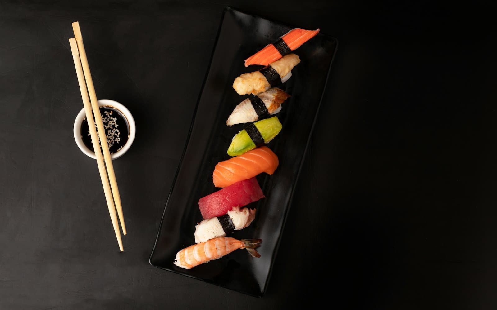 A row of hand-pressed nigiri on a black plate at Kamikoto, Sofia